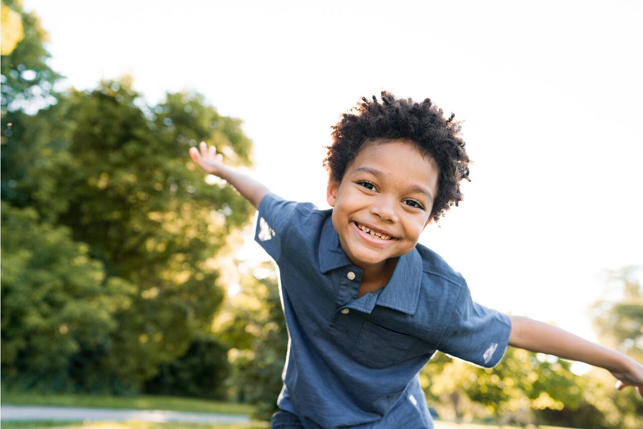 Happy boy playing outside with arms outstretched